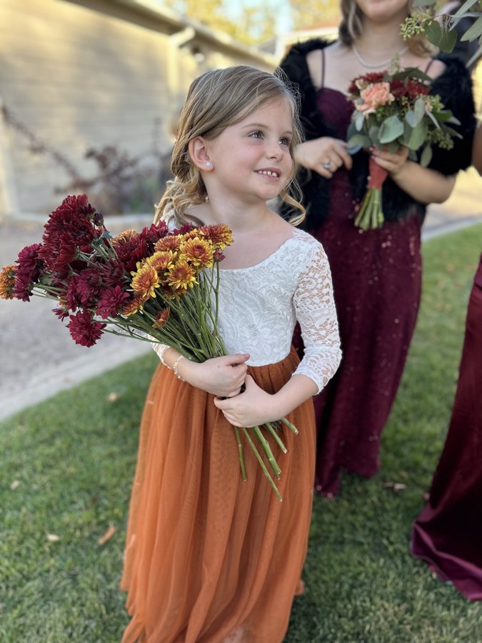 A flower girl holding an autumn bouquet